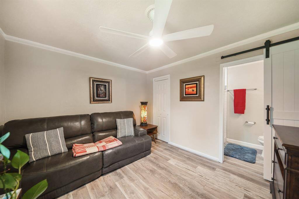 Cozy room with wood-style flooring, with a sliding barn door that leads to a bathroom, adding a modern touch.