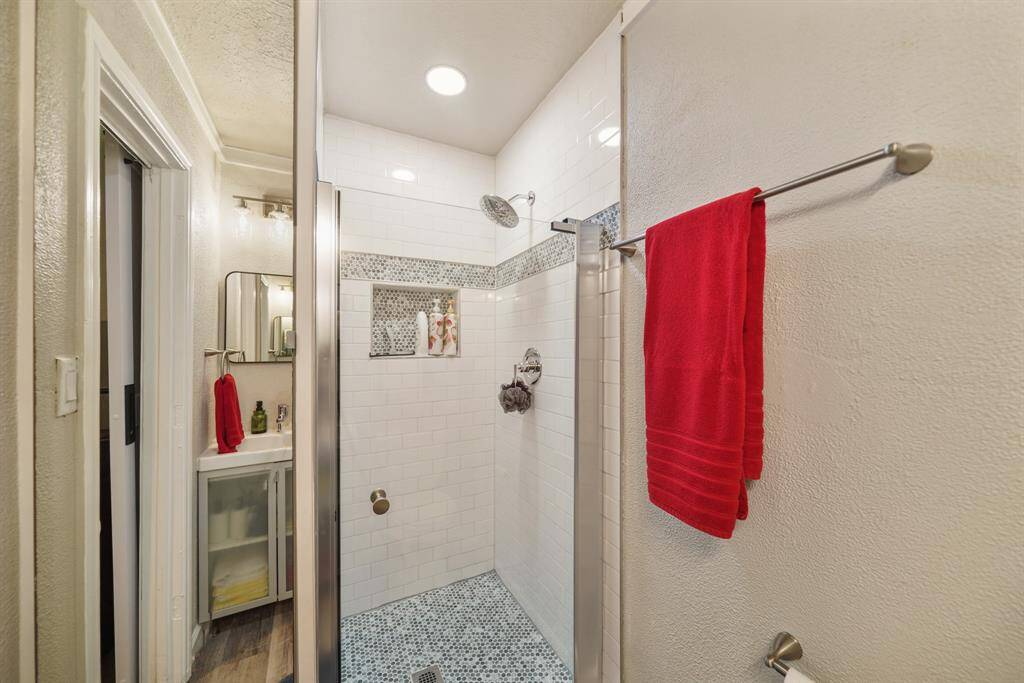 This bathroom features a modern shower with white subway tiles and a decorative mosaic accent. The vanity area is compact with a mirror and storage below.