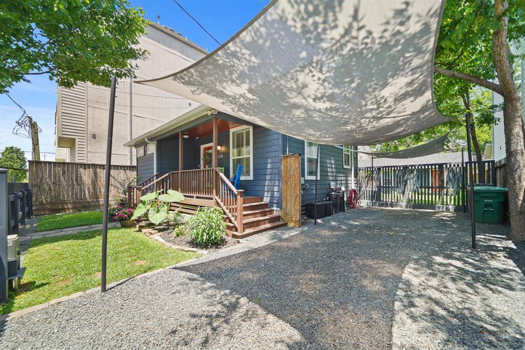 This cozy home features a charming backyard with a gravel area, shade sails, and a wooden deck perfect for relaxing or entertaining.