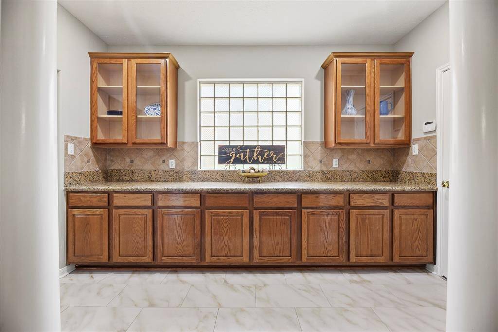 Expansive Butler's Pantry with a granite countertop and glass front cabinetry.