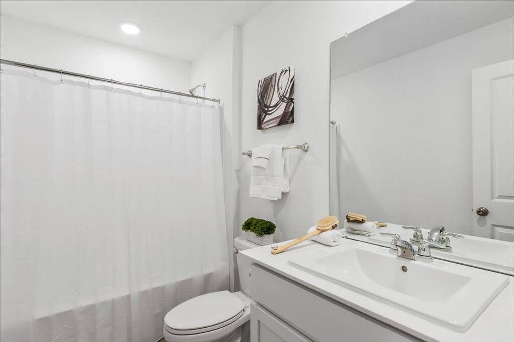 The secondary bathroom offers a white vanity with sink and a tub-shower combo, providing both style and functionality for everyday use.