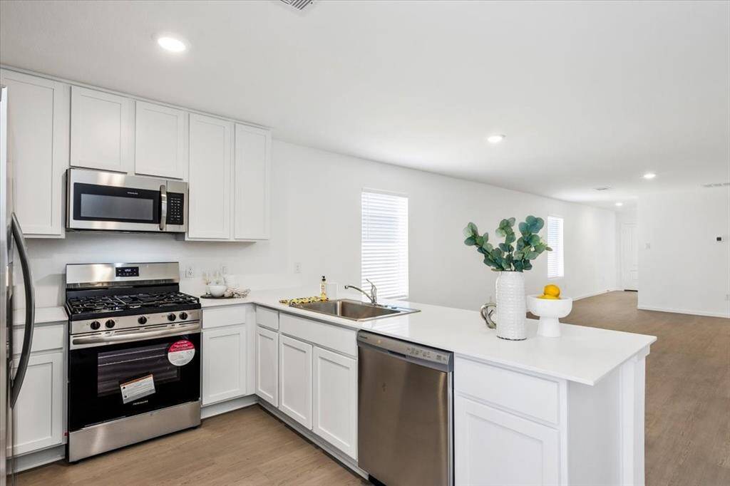 Light and bright kitchen featuring ample cabinetry, sleek quartz countertops, and an open layout seamlessly connecting to the living and dining areas. Open-concept living at its finest!
