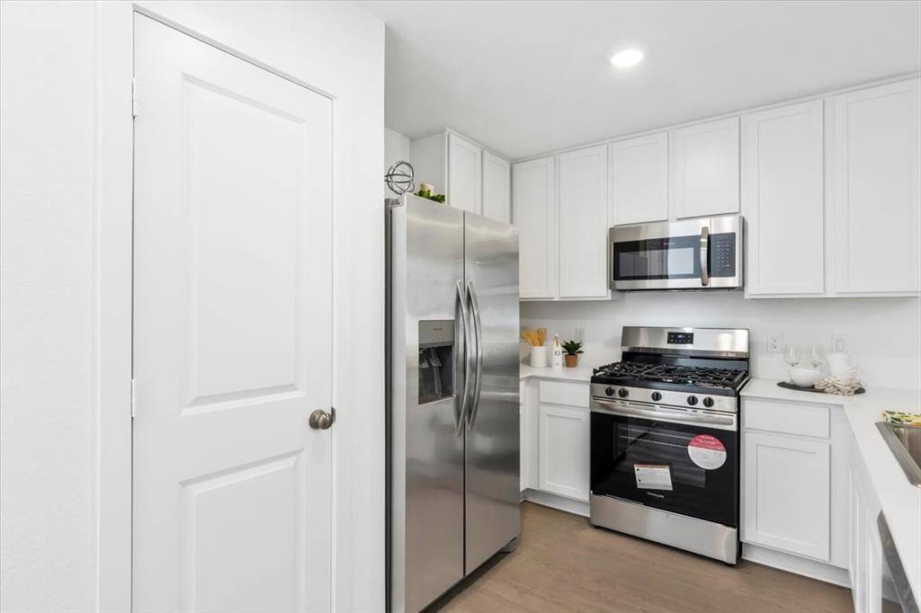 Spacious kitchen with a pantry and modern appliances, including a gas range, microwave, dishwasher, and refrigerator (included). Designed for both style and functionality!