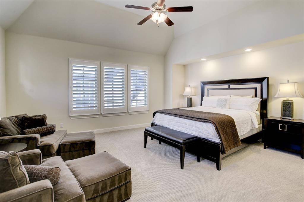 This Primary Suite features high ceilings, large windows with shutters for natural light, a comfortable cozy seating area, and neutral color walls.