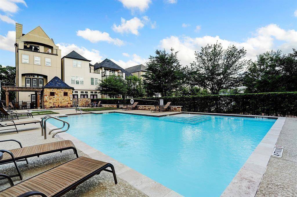 one of the community pool area with lounge chairs and surrounding greenery, perfect for relaxation.