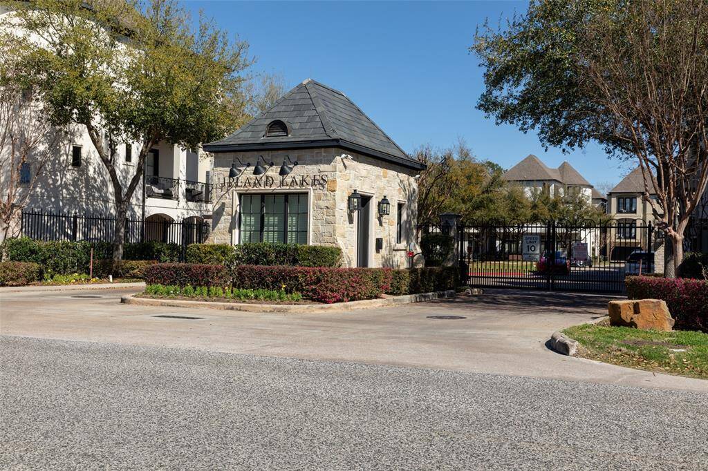 Gated entrance to a residential community surrounded by well-maintained landscaping and mature trees.