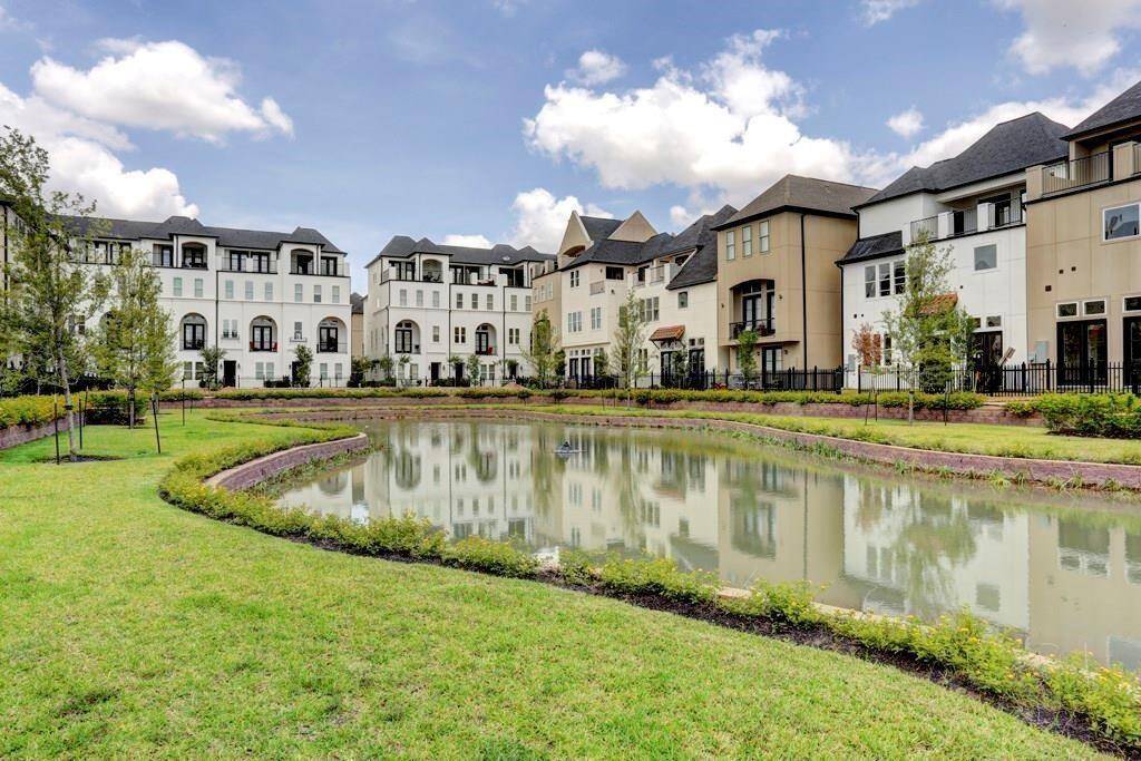 Charming neighborhood view featuring elegant homes with a scenic pond and landscaped greenery, creating a peaceful and inviting atmosphere.