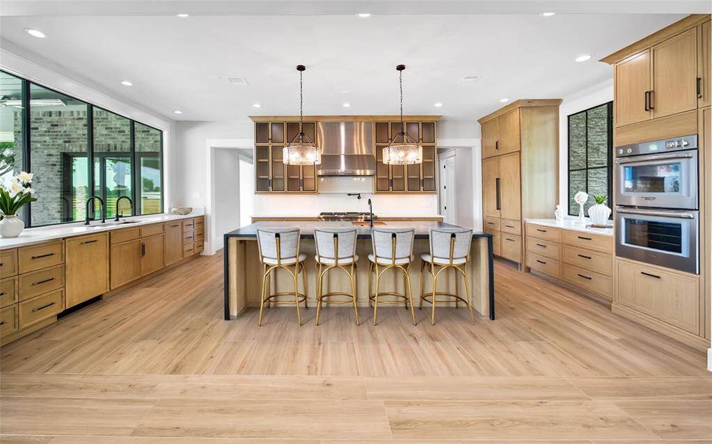 A large waterfall edge island has a secondary sink.  The granite stone was handpicked for its wood-grain design. Potfiller over the beautiful 6-burner and Griddle Professional Grade Thermador Gas Range.
