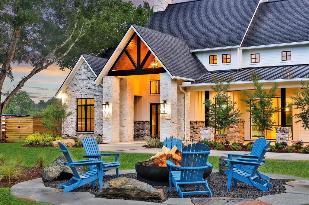 Elegantly-styled home with a stone and brick exterior and a large welcoming front porch. The landscaped yard includes a cozy outdoor seating area to entertain around a custom fire pit.  Set against a backdrop of mature trees and surrounded by nature, it is the perfect setting for relaxed entertainment.
