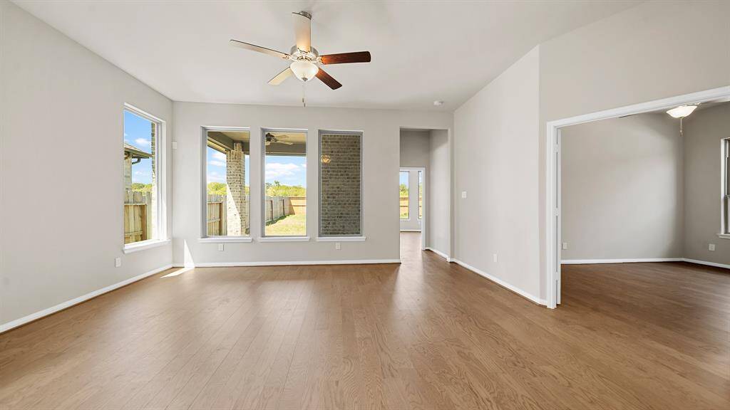 The Luxurious Living Room offers handsome hardwood flooring, ceiling fan and wall of windows overlooking the Beautiful Backyard.