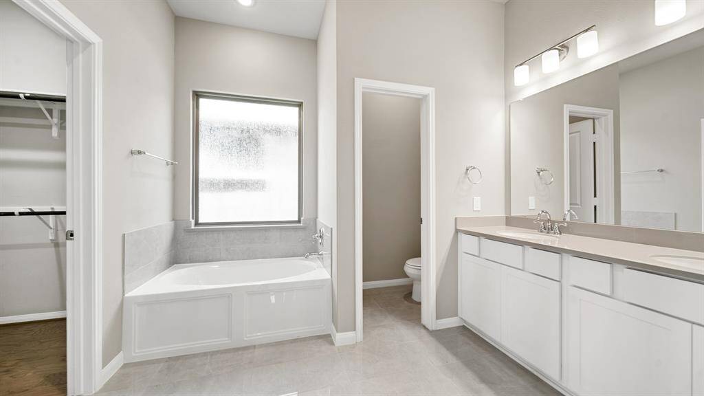 The Peaceful Primary Suite offers an oasis in your own home, with a glass encased shower with tile surround, dual sinks with extended countertops and a soaking tub with frosted window allowing natural light while maintaining privacy.