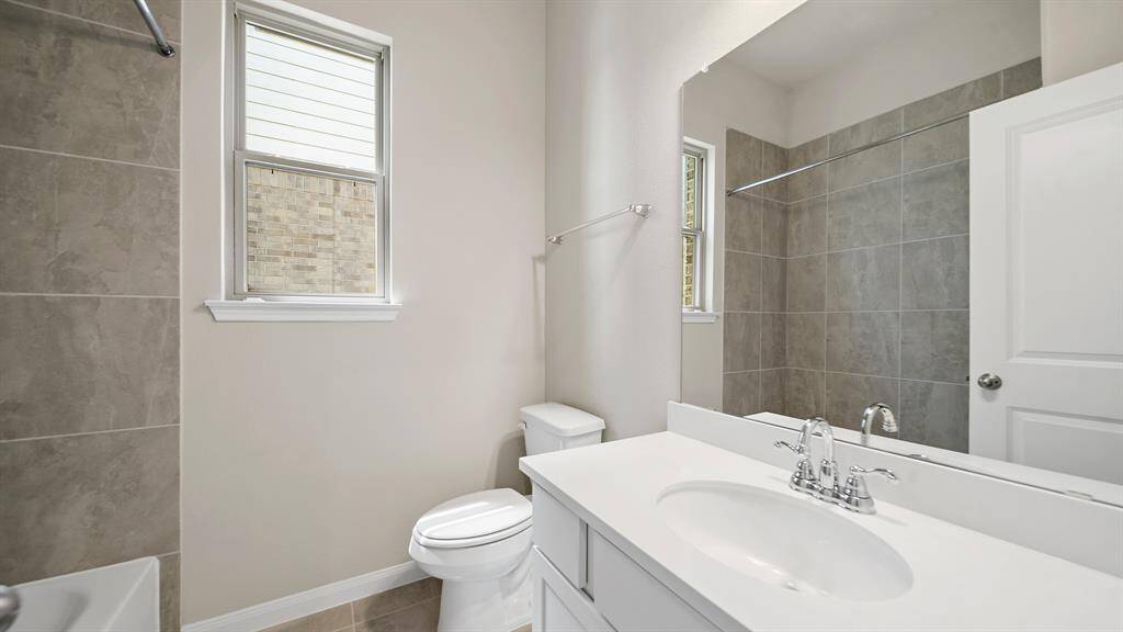 Secondary Bathroom with tile flooring, delicate white cabinetry and countertop and tub/shower combo with tile surround.
