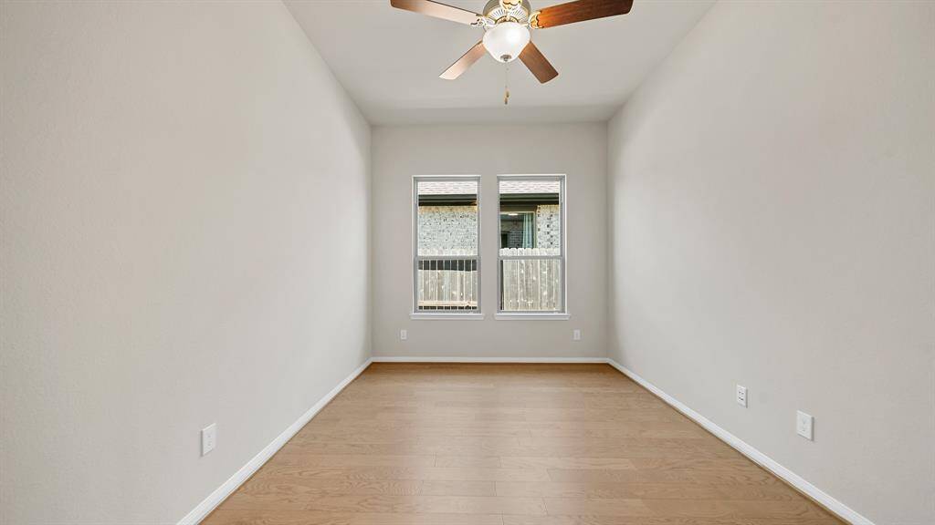 A look into another Splendid Secondary Bedroom that offers handsome hardwood flooring, natural lighting from windows, and easy access to the other living spaces within the home.