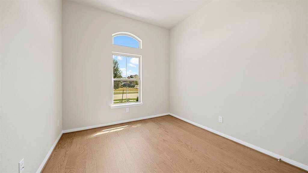 An additional Spacious Secondary Bedroom with handsome hardwood floors and large arched window overlooking the peaceful neighborhood.