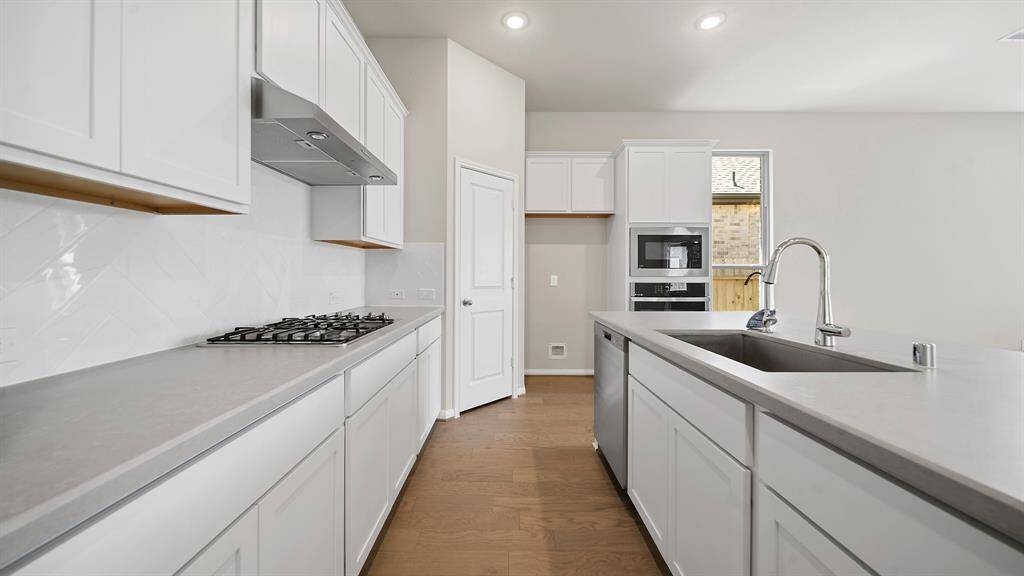 The Gourmet Kitchen boasts stainless steel appliances, delicate white cabinetry, large pantry and breakfast bar for additional seating.