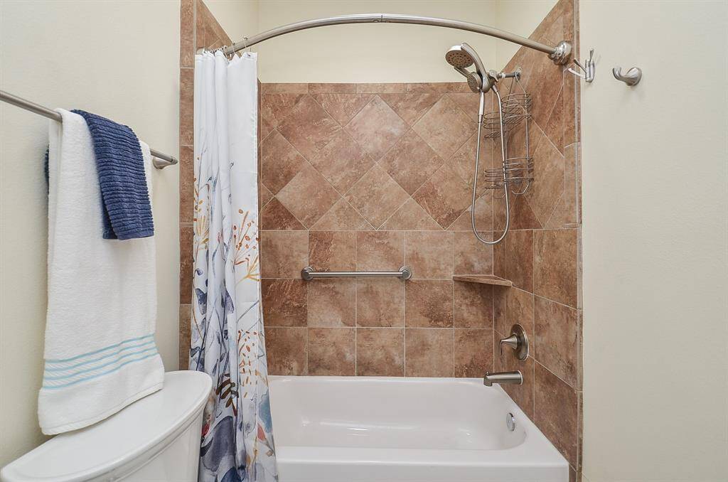 Comfort meets everyday ease. This secondary bath features a tiled tub-shower combo, curved shower rod, and handheld showerhead—perfect for relaxed routines, shared spaces, or winding down after a long day.