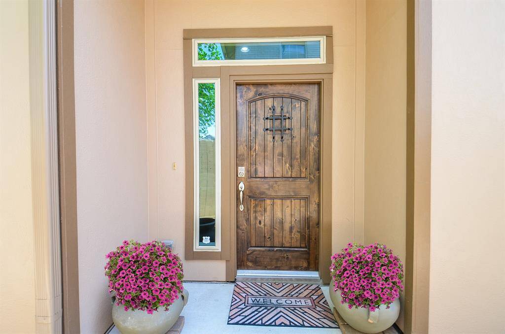 Come on in. This restained wood door, framed by tall windows and cheerful blooms, sets the tone just right. It’s the kind of entry that says “you’re home” before you even step inside.