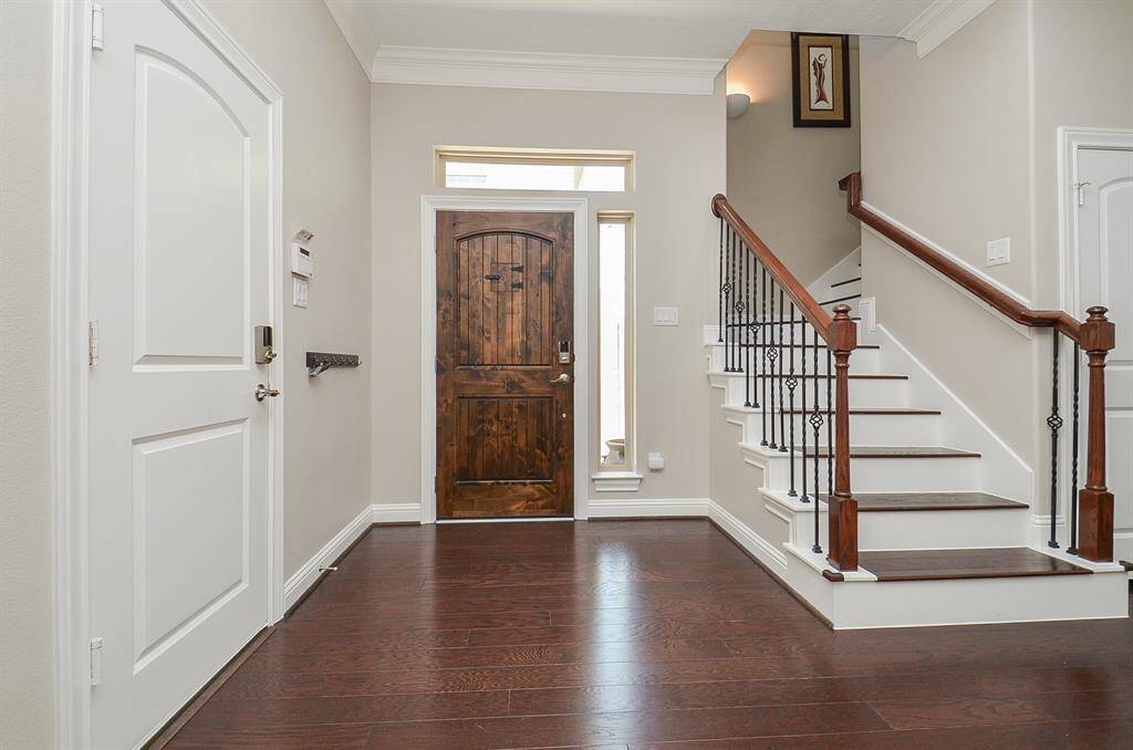 Step inside and feel the warmth. From the rich wood front door to the elegant staircase and hardwood floors, this entryway makes every homecoming feel special—and every guest feel instantly welcome.
