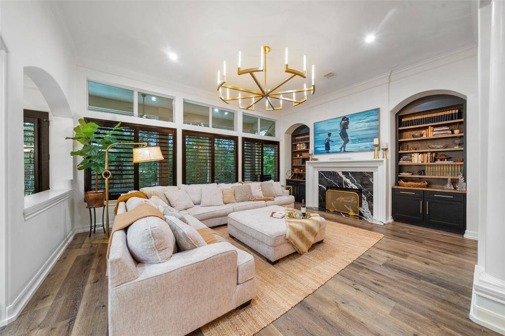 The living room has been renovated with Nero Marquina marble on the gas log fireplace, custom cabinets w/new hardware on each side, custom light fixture and custom shutters.