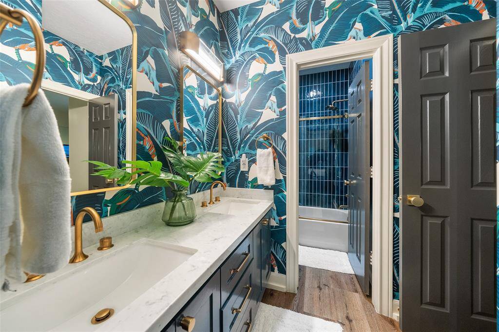 Guest bathroom with Martinique Wallpaper called "The Original Banana Leaf Print". Dual sinks, update hardware and lighting, sliding glass door. GORGEOUS!