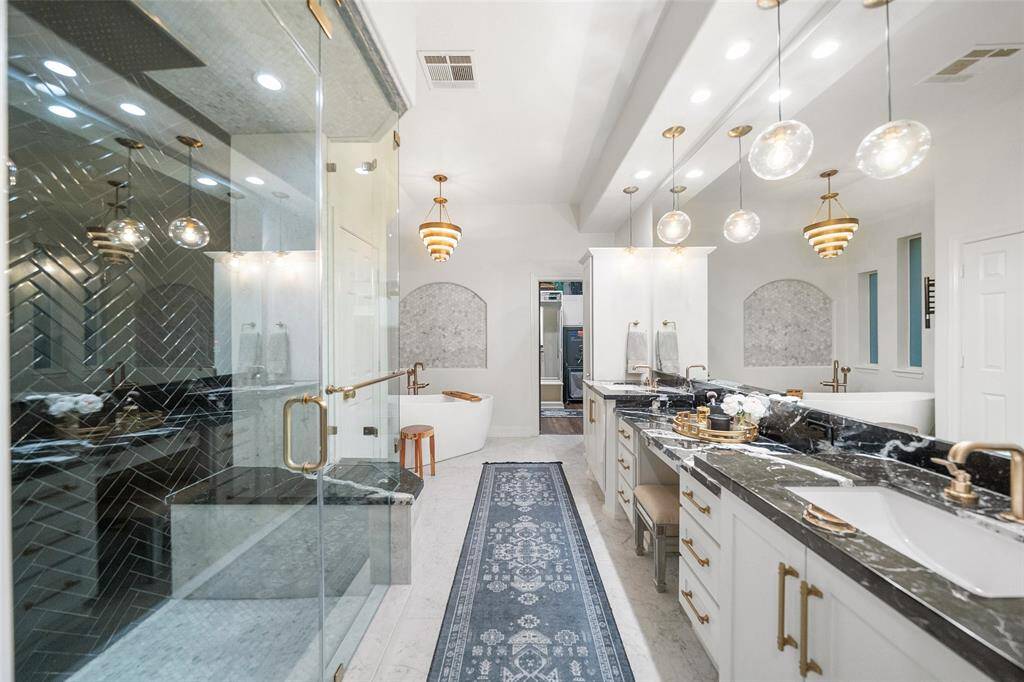 The Primary Bathroom offers a serene vibe from the Aromatherapy Steam shower to the soak tub with a towel warming rack. The countertops feature Nero Marquina marble and custom pendant lighting and new hardware.