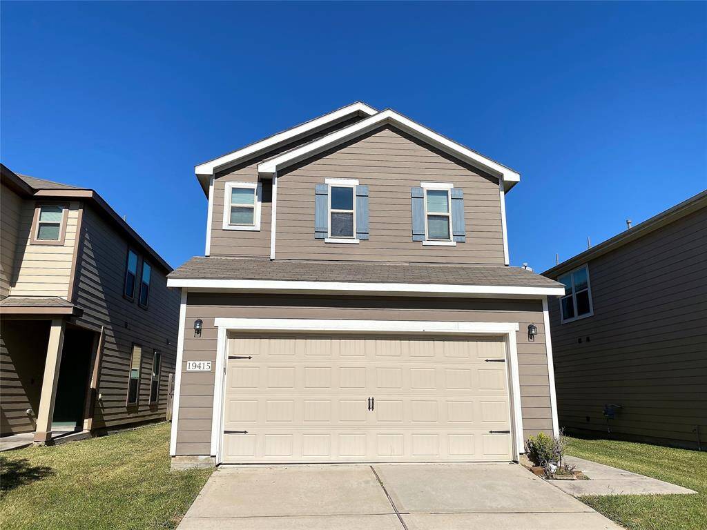 This is a two-story, modern home with a neutral exterior and a two-car garage. The front yard is well-maintained, and the house features clean lines and a simple design. It's situated closely between two neighboring homes.