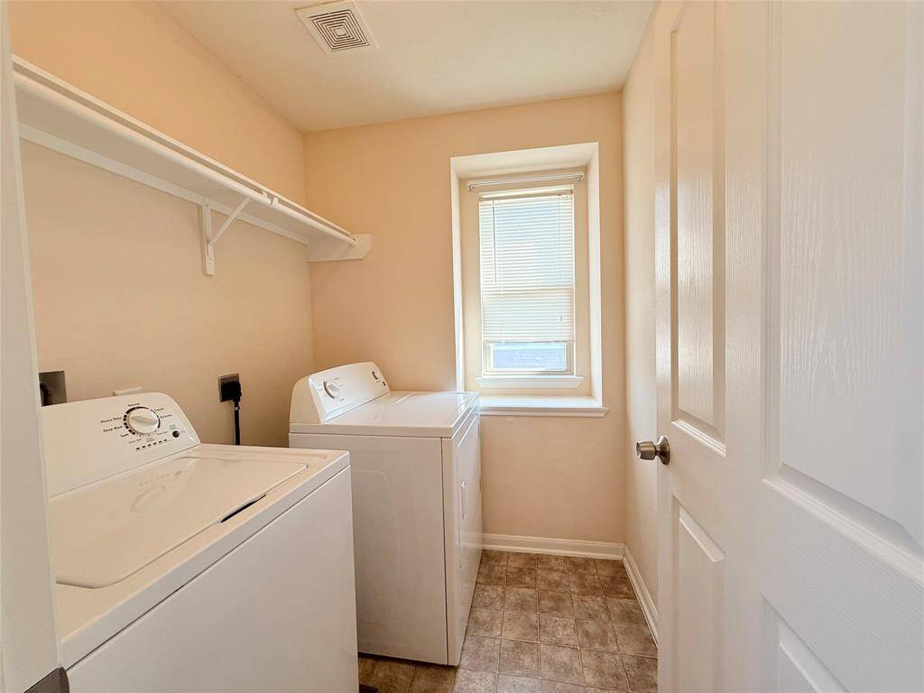 This photo shows a bright, carpeted upstairs landing with a staircase featuring a decorative iron railing. The space is well-lit with recessed lighting and two windows, offering a cozy and open feel.
