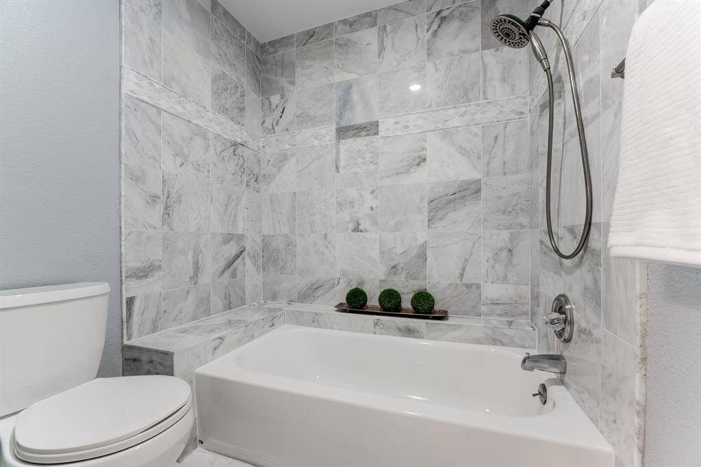 Enjoy a luxurious soak or a refreshing shower in this large custom tiled bathtub with a built-in shower.