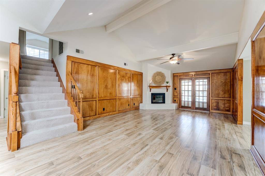 Relax and unwind in this inviting living room featuring vaulted ceilings, recessed lighting, a stunning gas fireplace with a custom mantle, and elegant solid wood paneling.