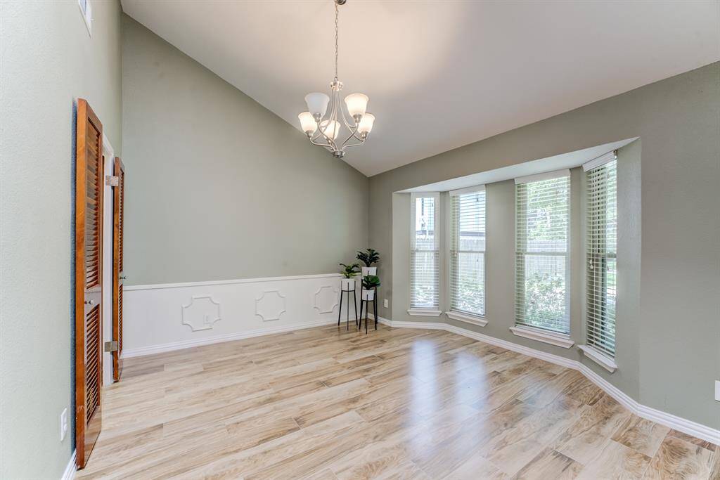 Enjoy meals in this bright and airy dining room featuring soaring high ceilings, charming bay windows, sophisticated wainscot walls, and a stylish light fixture.