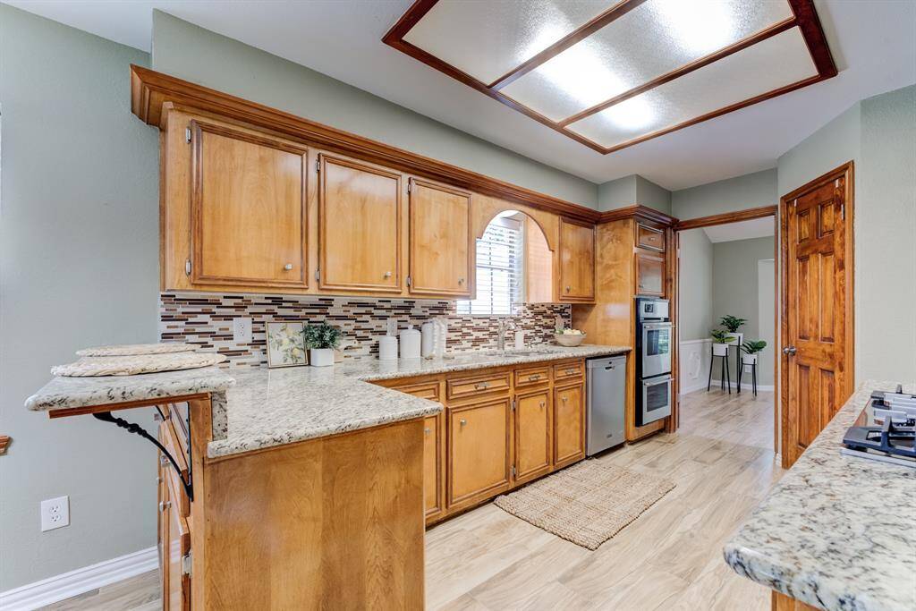 Enjoy cooking in a spacious and well-appointed kitchen with granite countertops, easy-to-clean stainless steel appliances, ample natural light from the window over the sink, and a beautiful custom tiled backsplash.