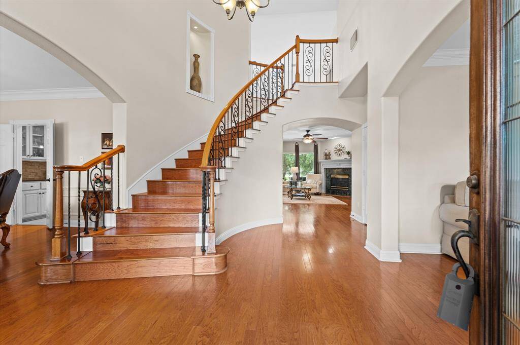 The grand foyer with elegant curved staircase with decorative iron spindles.