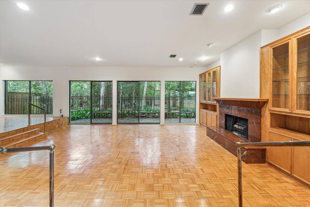 The living space is lined with a wall of sliding glass doors that overlook a wooded trail.