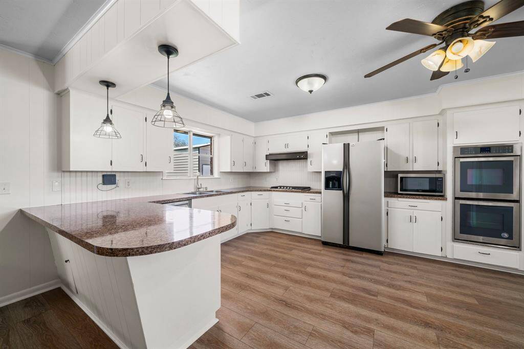 Beauty and function combine is this sleek updated kitchen. Freshly painted white cabinets with new hardware.  Stainless appliances including double ovens and a 4 burner gas cooktop with griddle. The breakfast bar is perfect for those meals on the go. Refrigerator conveys.