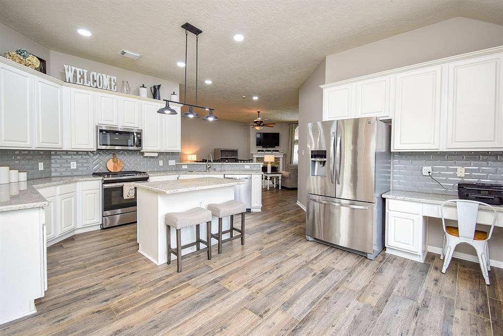 Covered patio is ideal for outdoor living year-round. Featuring a rich wood deck and a pergola-style roof with string lighting and a ceiling fan, this space is made for entertaining or relaxing in comfort.