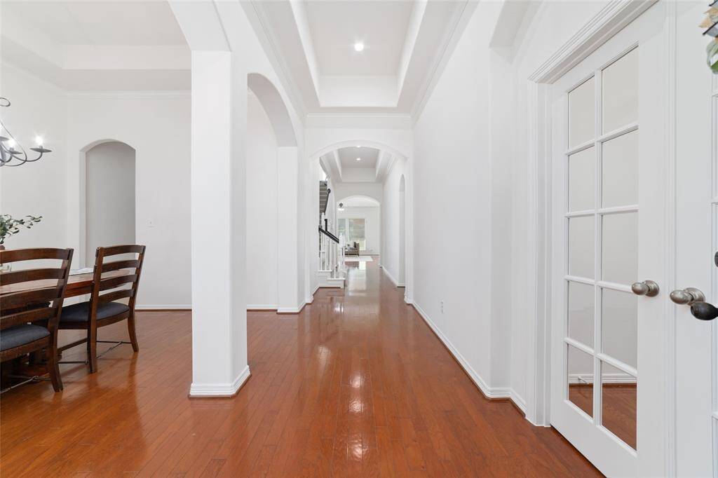 As you enter the home, you are greeted by a bright, spacious hallway with elegant archways and hardwood floors. Fresh neutral paint throughout and tall ceilings.  On the left, there's a dining area with a chandelier, and on the right, French doors lead to a spacious study with lots of built ins.