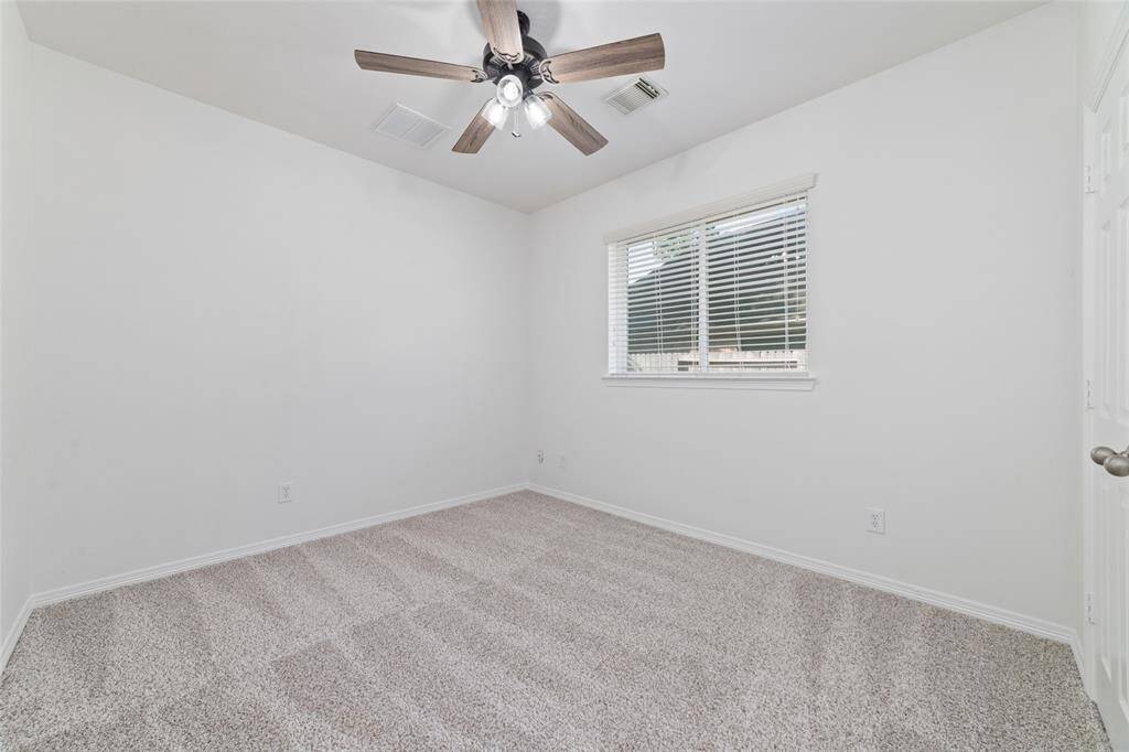 The second of the secondary bedrooms features neutral walls, soft carpet, a ceiling fan, and a window with blinds, offering a cozy and inviting space.