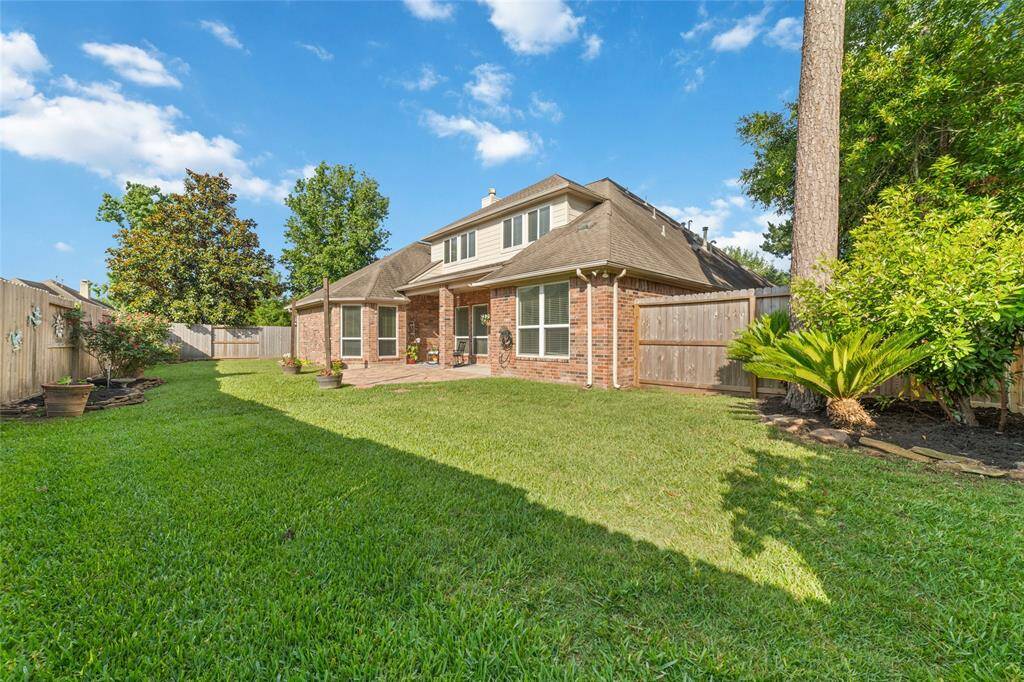 Another view of the spacious backyard with landscaping, sprinklers, and space for a pool.