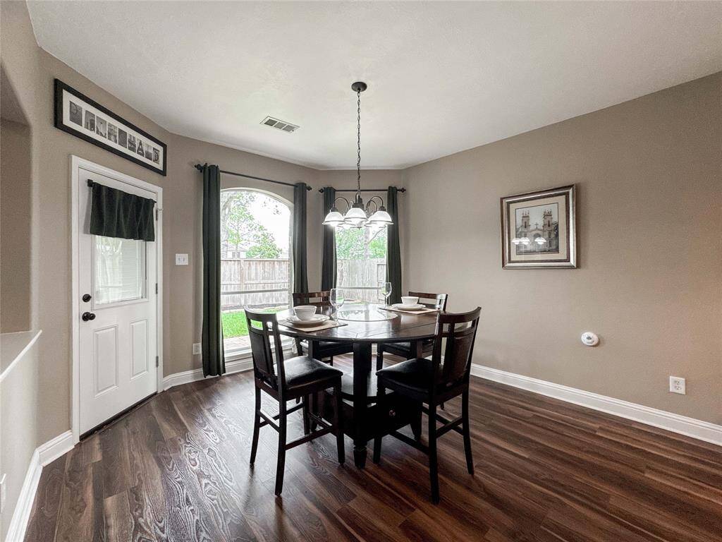 This photo showcases the breakfast nook with a backdrop of large windows. The space features hardwood floors, neutral walls, and ample natural light, creating an inviting atmosphere.
