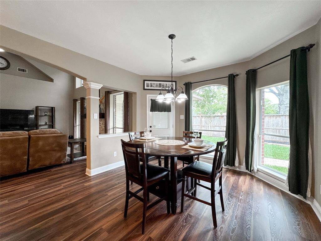 This inviting breakfast nook area features wood flooring, abundant natural light from large windows, and an open layout that connects seamlessly to the living space. Perfect for family meals and entertaining.