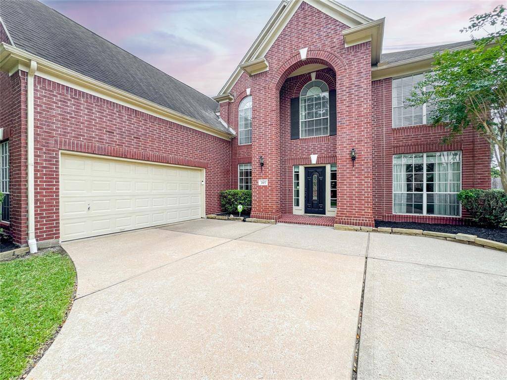 The entrance features a grand arched window and double doors, surrounded by well-maintained landscaping.