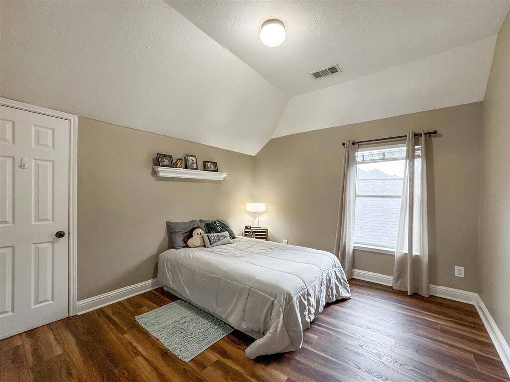 This secondary bedroom is found upstairs and features a cozy, minimalist design with warm luxury vinyl flooring and neutral-walls.