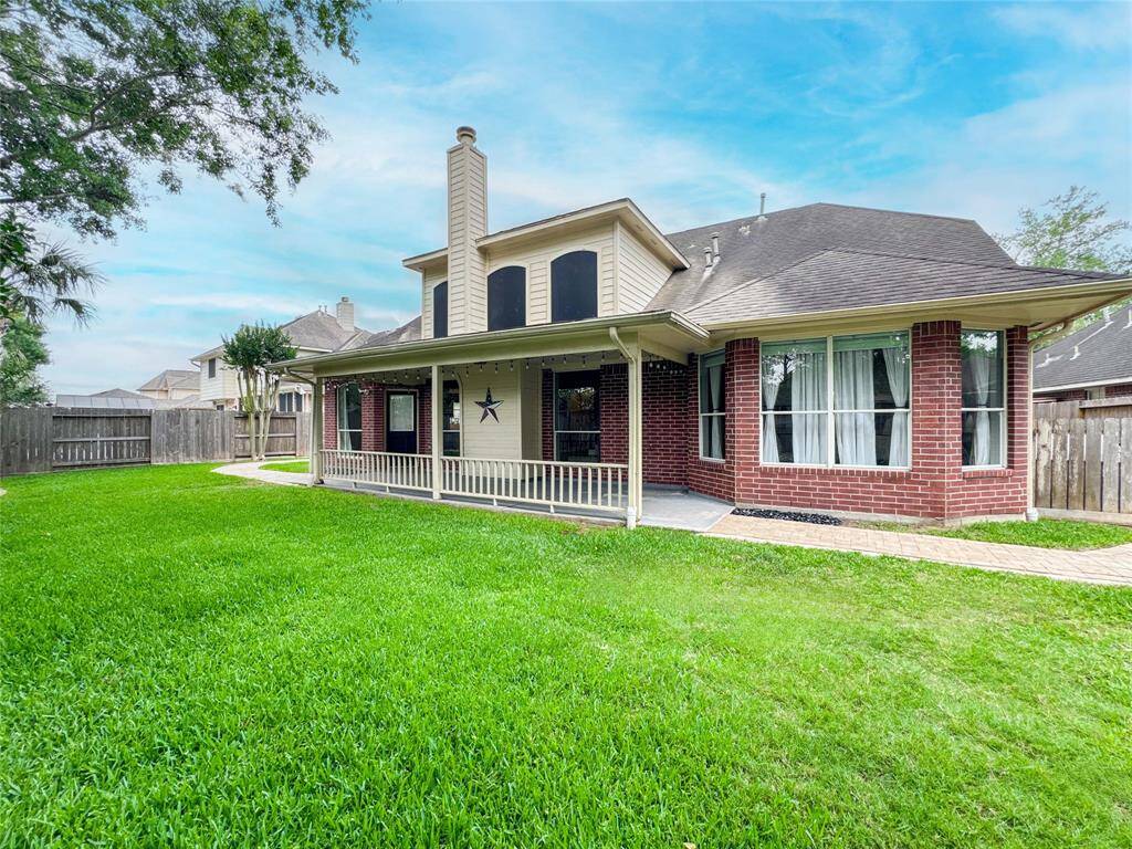 Charming two-story home with a covered patio and spacious backyard, perfect for outdoor activities. Features a brick exterior, large windows, and a fenced yard for privacy.