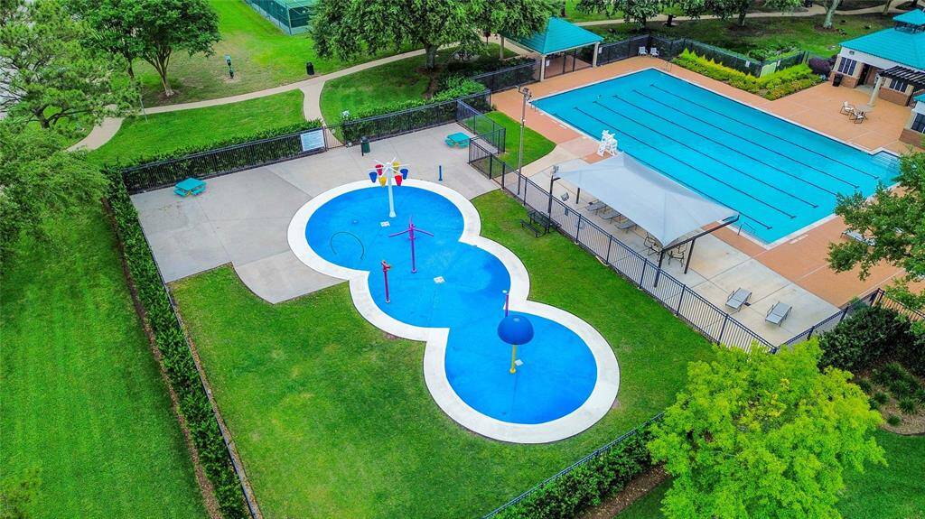 This aerial photo showcases the Brittany Lakes Park & Pool community recreational area featuring a large, fenced swimming pool with lap lanes, a nearby splash pad