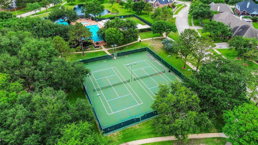 This aerial photo showcases a well-maintained Brittany Lakes Park & Pool community tennis court and a nearby pool area, surrounded by mature trees.