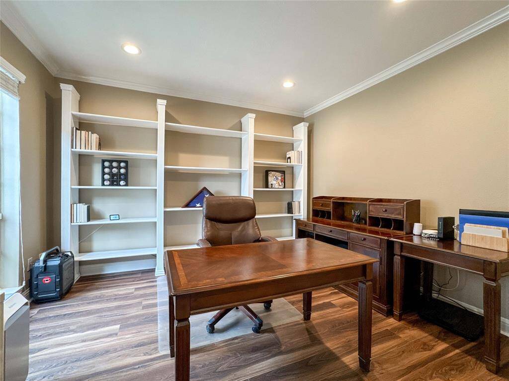 The home office showcases built-in white shelving, recessed lighting, wood flooring, and neutral paint creating a professional and organized workspace.
