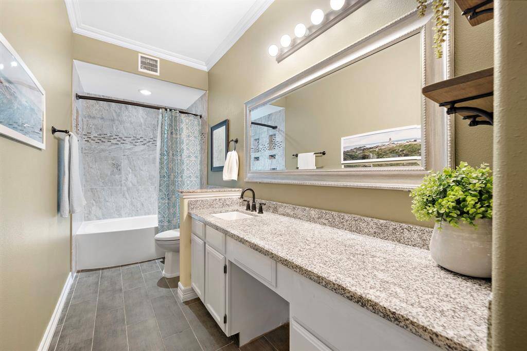 Accessible from the entertainment areas and secondary bedroom, this full bath showcases a shower/tub combo with a custom tile surround and a vanity area with spacious countertops and built-ins for extra storage.