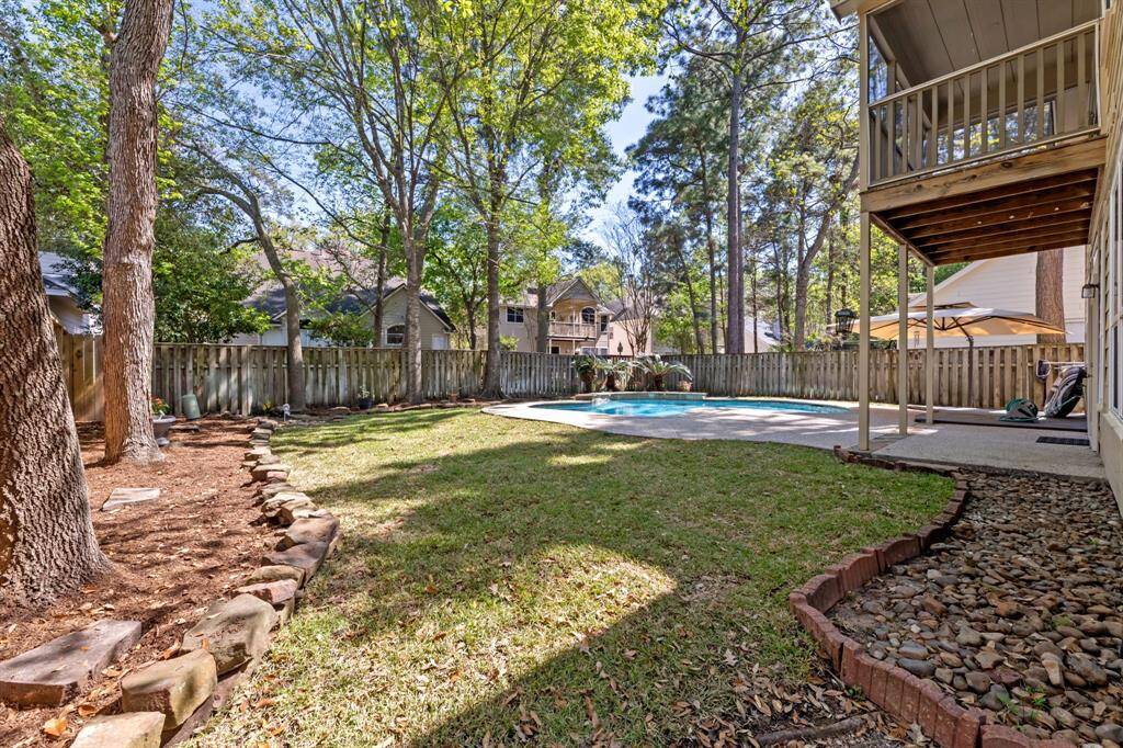 This spacious backyard features a well-maintained lawn with mature trees, a cozy stone-bordered garden, and a fenced perimeter for privacy. It includes a refreshing pool with a surrounding patio area, perfect for outdoor relaxation and entertainment.