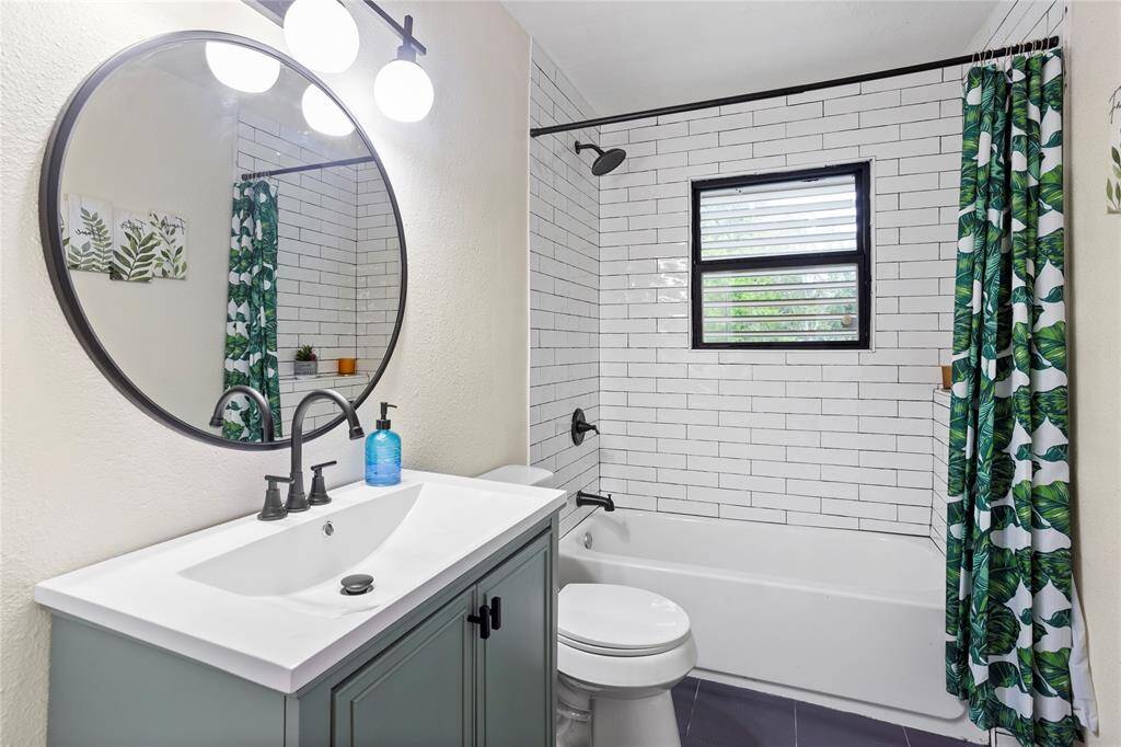 bathroom updated with new tile on tub backsplash, floor, new vanity, mirror & lighting
