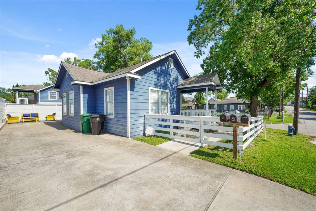 Charming blue cottage theme triplex with white trim, featuring a small front porch and a spacious driveway. The home is set on a corner lot with a fenced yard and mature trees, providing shade and privacy. Ideal for those seeking a cozy, inviting space near tons of major areas in the city